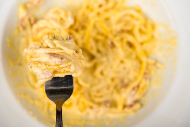 Bovenaanzicht van vork met kaasachtige spaghetti pasta