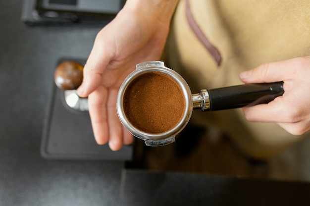 Bovenaanzicht van vrouwelijke barista koffiemachine beker te houden