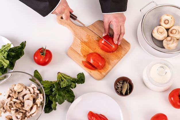 Bovenaanzicht van vrouwelijke chef-kok snijden tomaten