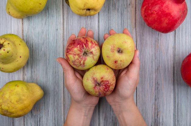 Bovenaanzicht van vrouwelijke handen met verse appels op een grijze houten achtergrond