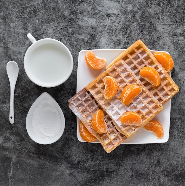 Bovenaanzicht van wafels met mandarijnen en melk