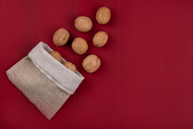Bovenaanzicht van walnoten in een jutezak op een rode ondergrond