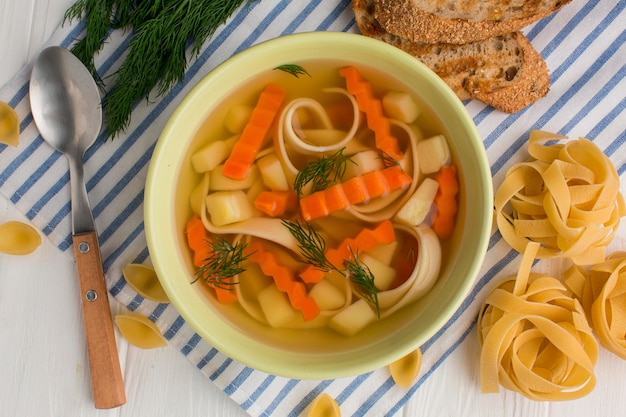 Bovenaanzicht van winter groentesoep in kom met tagliatelle en toast