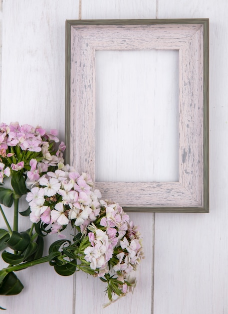 Bovenaanzicht van wit frame met bloemen op een wit oppervlak