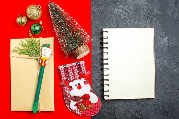 Bovenaanzicht van xsmas stemming met kerstboom decoratie accessoires cadeau sok naast notebook op rode en zwarte achtergrondgeluid