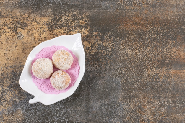 Gratis foto bovenaanzicht van zelfgemaakte verse lekkere koekjes op witte plaat over rustieke tafel.