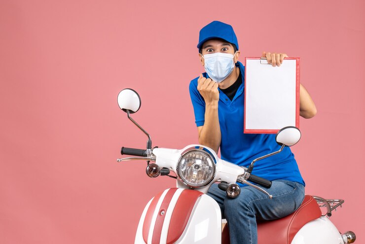 Gratis Foto bovenaanzicht van zelfverzekerde mannelijke bezorger in masker met hoed zittend op scooter met document op pastel perzik achtergrond