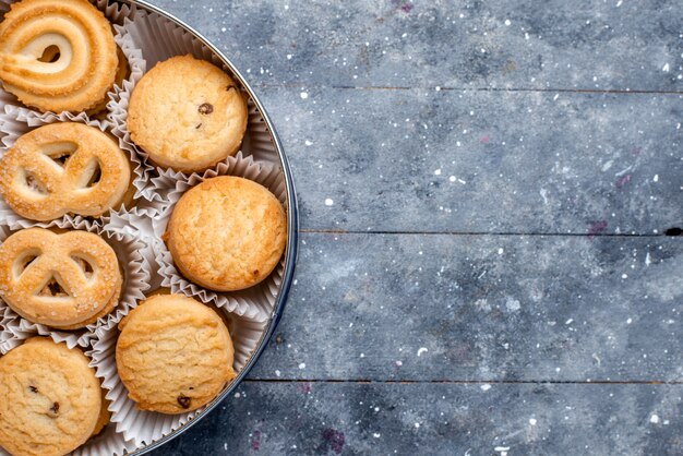 Bovenaanzicht van zoete heerlijke koekjes anders gevormd binnen rond pakket op grijs