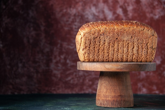 Gratis foto bovenaanzicht van zwart brood aan de linkerkant op snijplank op gemengde kleuren noodlijdende achtergrond met vrije ruimte