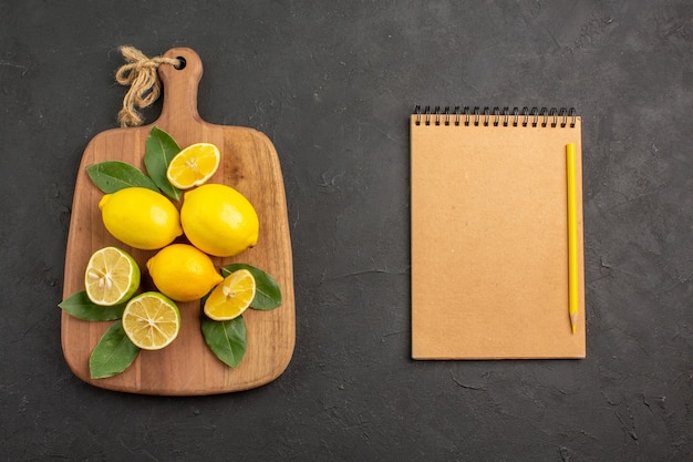Gratis foto bovenaanzicht vers citroenen zuur fruit op de donkergrijze tafel citrus limoen fruit