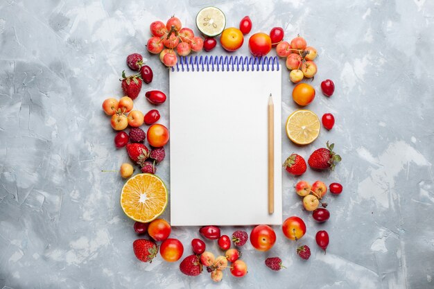 Bovenaanzicht vers fruit citroenen en kersen met blocnote op wit bureau fruit rijpe verse zachte vitamine