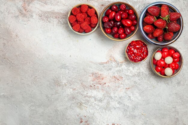 Bovenaanzicht vers fruit frambozen aardbeien en kornoeljes met koekjes op witte ruimte