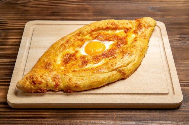 Bovenaanzicht vers gebakken brood met gekookt ei op een bruin houten bureau deeg maaltijd broodje ontbijt eivoer