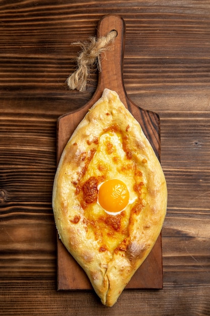 Bovenaanzicht vers gebakken brood met gekookt ei op houten oppervlak brood deeg broodje eten ontbijt