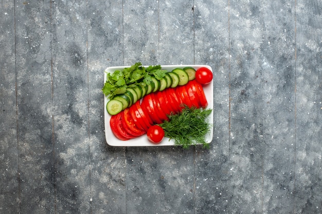 Bovenaanzicht vers gesneden tomaten elegant ontworpen salade op grijze rustieke ruimte