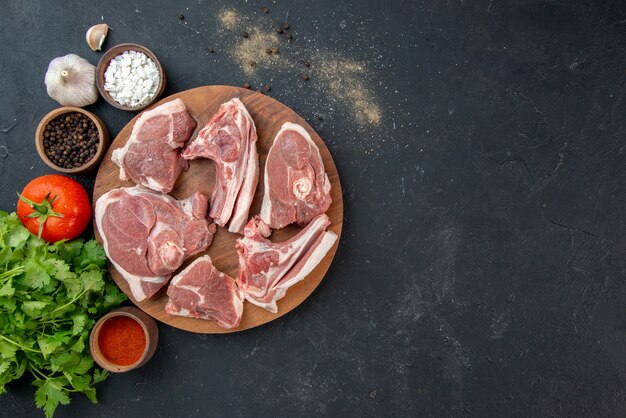 Bovenaanzicht vers vlees plakjes rauw vlees met kruiden en groenten op een donkere keuken salade maaltijd versheid koe voedsel dier