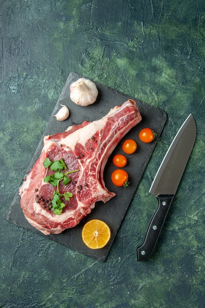 Gratis foto bovenaanzicht vers vleesplakje met oranje tomaten op donkerblauwe achtergrond voedsel vlees keuken dier kip kleur koe slager