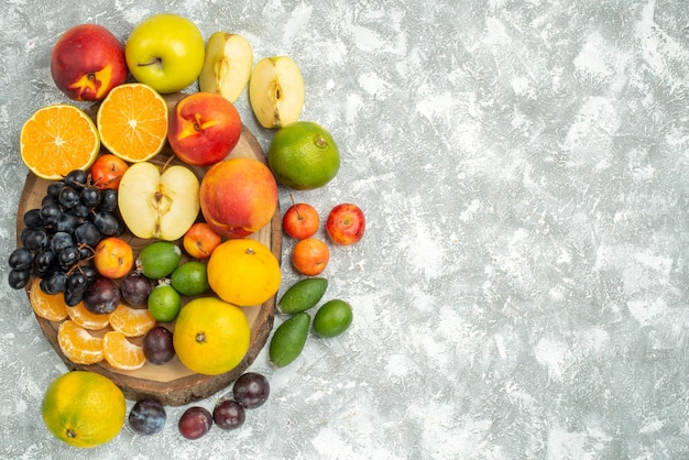 Bovenaanzicht verschillende fruitsamenstelling gesneden en geheel vers fruit op witte achtergrond boom vitamine rijp fruit zachte kleur