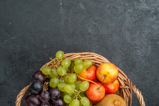 Bovenaanzicht verschillende fruitsamenstelling vers en rijp in de mand op de donkergrijze achtergrond zacht vers fruit gezondheid rijp