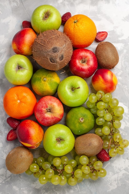 Gratis foto bovenaanzicht verschillende fruitsamenstelling vers fruit op wit bureau