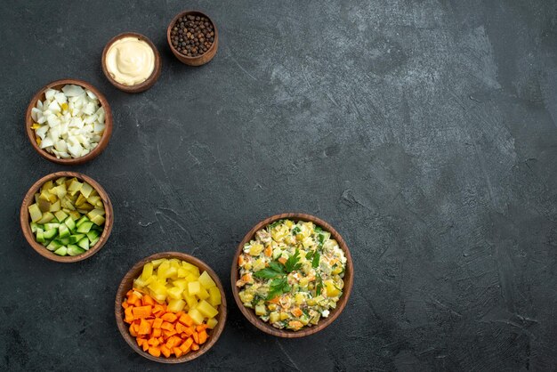Bovenaanzicht verschillende gesneden groenten in potten op grijze oppervlaktemaaltijd snacksalade
