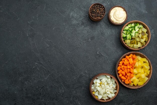 Bovenaanzicht verschillende gesneden groenten op de donkere oppervlakte maaltijd snack groentesalade