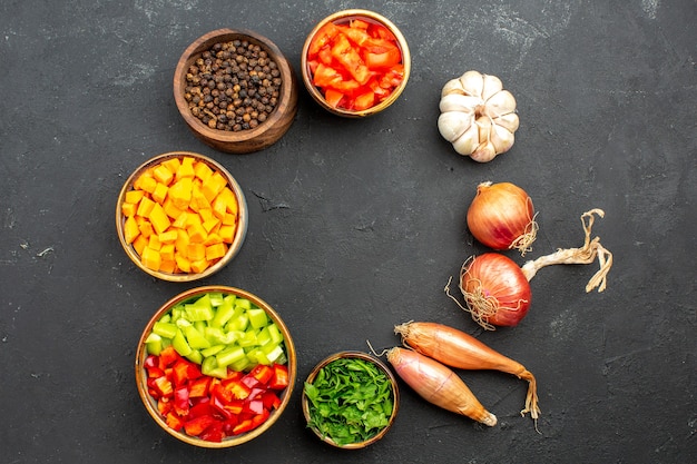 Bovenaanzicht verschillende gesneden paprika's met greens en kruiden op grijze ruimte