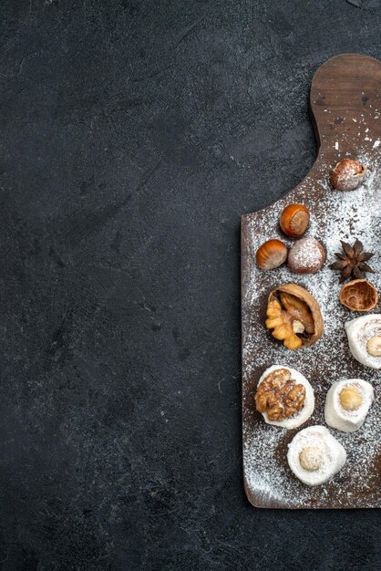 Bovenaanzicht verschillende koekjes met cake en walnoten op het donkergrijze bureau