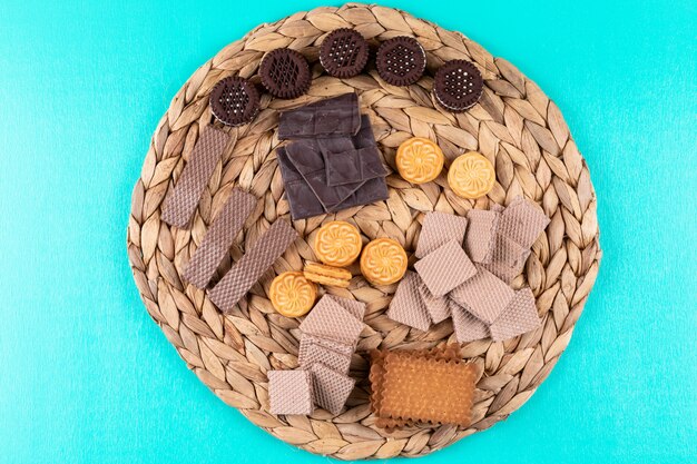 bovenaanzicht verschillende koekjes wafels en chocolade op blauwe ondergrond