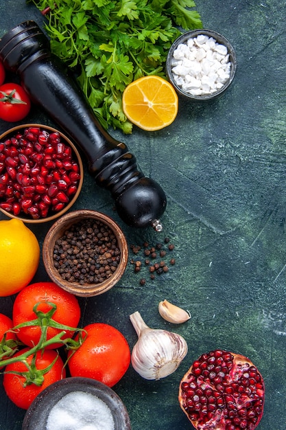 Gratis foto bovenaanzicht verschillende kruiden pepermolen tomaten knoflook greens granaatappel op tafel