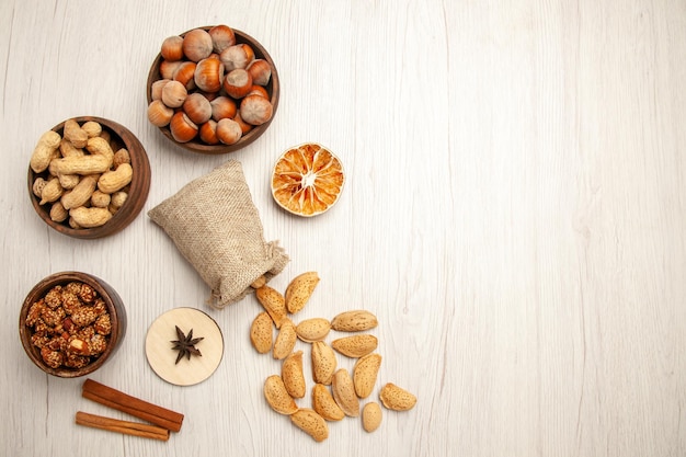 Bovenaanzicht verschillende noten in kleine potjes op witte bureaunoot snack walnoot hazelnoot