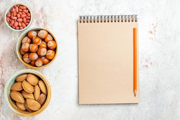 Bovenaanzicht verschillende noten in kleine potten op de witte achtergrond noot snack verse walnoot hazelnoot pinda