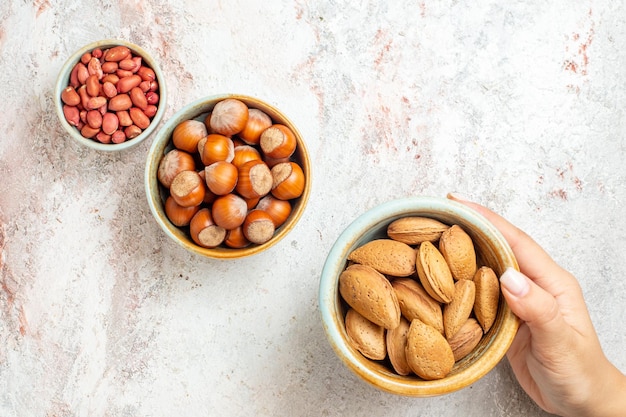 Bovenaanzicht verschillende noten in kleine potten op witte achtergrond noten snack verse walnoot hazelnoot pinda