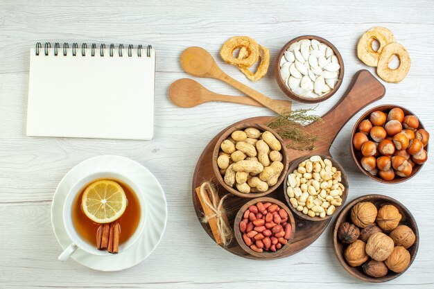 Bovenaanzicht verschillende noten pinda's hazelnoten en walnoten met kopje thee op witte tafel