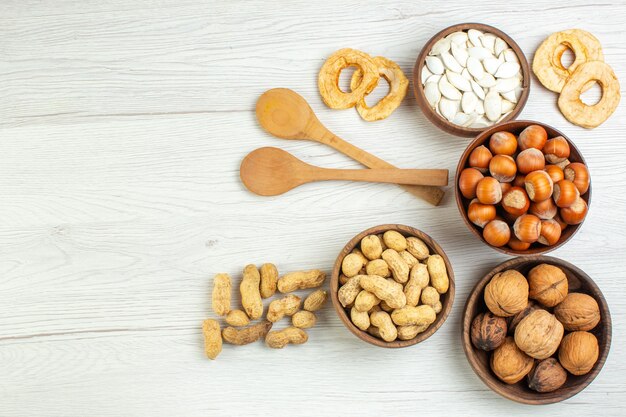 Bovenaanzicht verschillende noten, pinda's, hazelnoten en walnoten op witte tafel