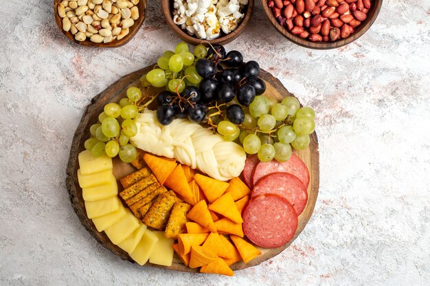 Bovenaanzicht verschillende snacks verse druiven kaas cips met noten op witte ruimte