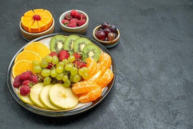 Bovenaanzicht verschillende soorten fruit samenstelling vers en gesneden fruit op de donkere achtergrond gezondheid rijp vers fruit zacht