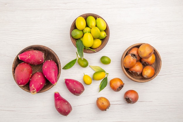 Bovenaanzicht verschillende vers fruit binnen platen op wit bureau fruit tropisch rijp dieet exotische kleur