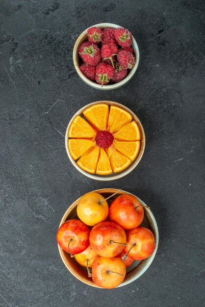 Gratis foto bovenaanzicht verschillende vruchten samenstelling in kleine potten op donkere achtergrond zacht vers fruit gezondheid rijp