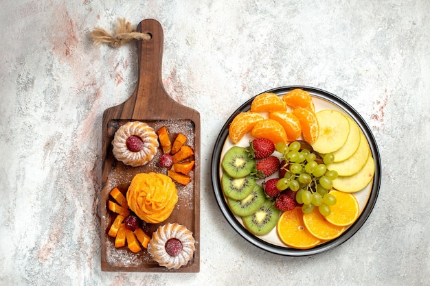 Gratis foto bovenaanzicht verschillende vruchten samenstelling vers en gesneden fruit op witte achtergrond rijp fruit zachte kleur gezondheid