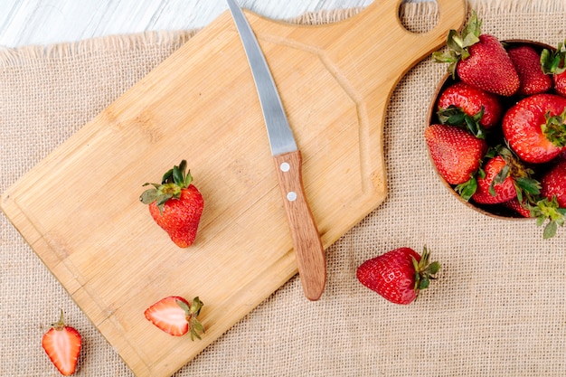 Bovenaanzicht verse aardbeien in een kom en mes op een bord