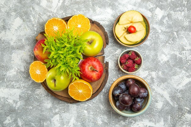 Bovenaanzicht verse appels met gesneden sinaasappelen en pruimen op witte achtergrond rijp zacht fruit verse appel