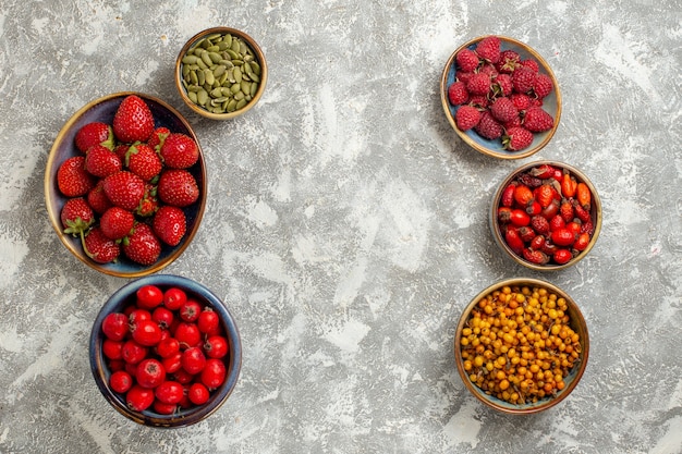 Gratis foto bovenaanzicht verse bessen fruit in platen op witte achtergrond