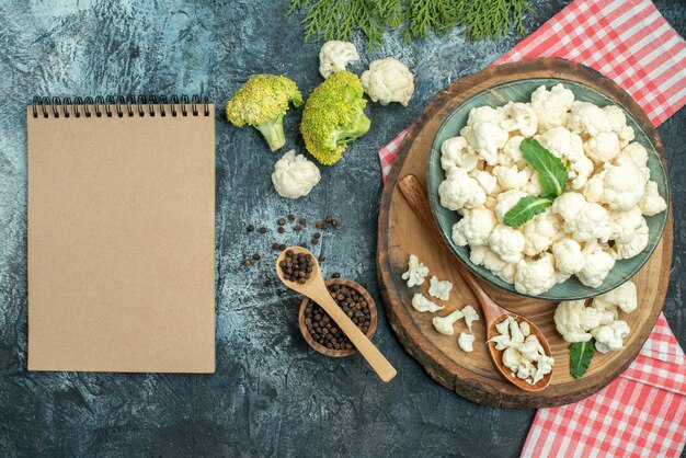 Bovenaanzicht verse bloemkool met lepels en peper op de lichtgrijze tafel