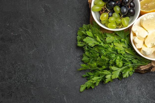 Bovenaanzicht verse druiven met witte kaas greens en citroen op donkere oppervlakte maaltijd fruit melk voedsel