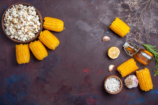 Bovenaanzicht verse gele likdoorns met popcorn op het donkere oppervlak maïs snack eten rauw vers