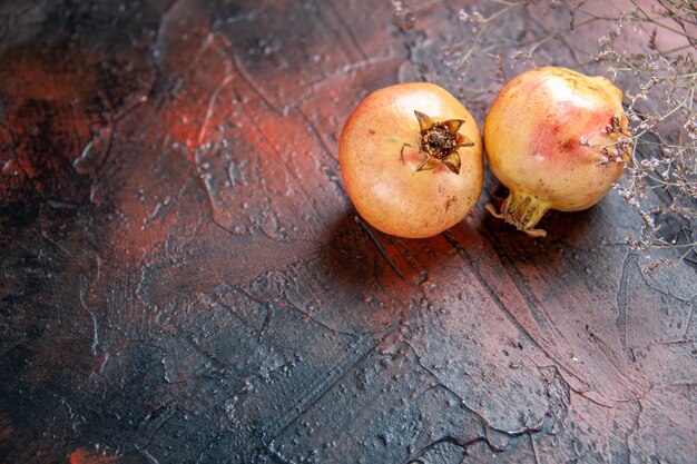 Bovenaanzicht verse granaatappels gedroogde wilde bloementak op donkerrode achtergrond