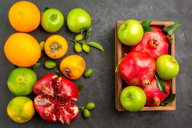 Bovenaanzicht verse granaatappels met appels en ander fruit op donkere oppervlakte rijp fruit kleur