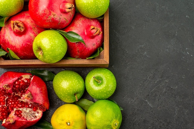 Bovenaanzicht verse granaatappels met mandarijnen en appels op het donkere oppervlak rijp kleurenfruit