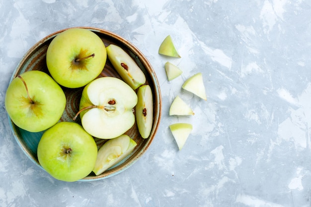 Bovenaanzicht verse groene appels gesneden en hele vruchten op lichtwit oppervlak